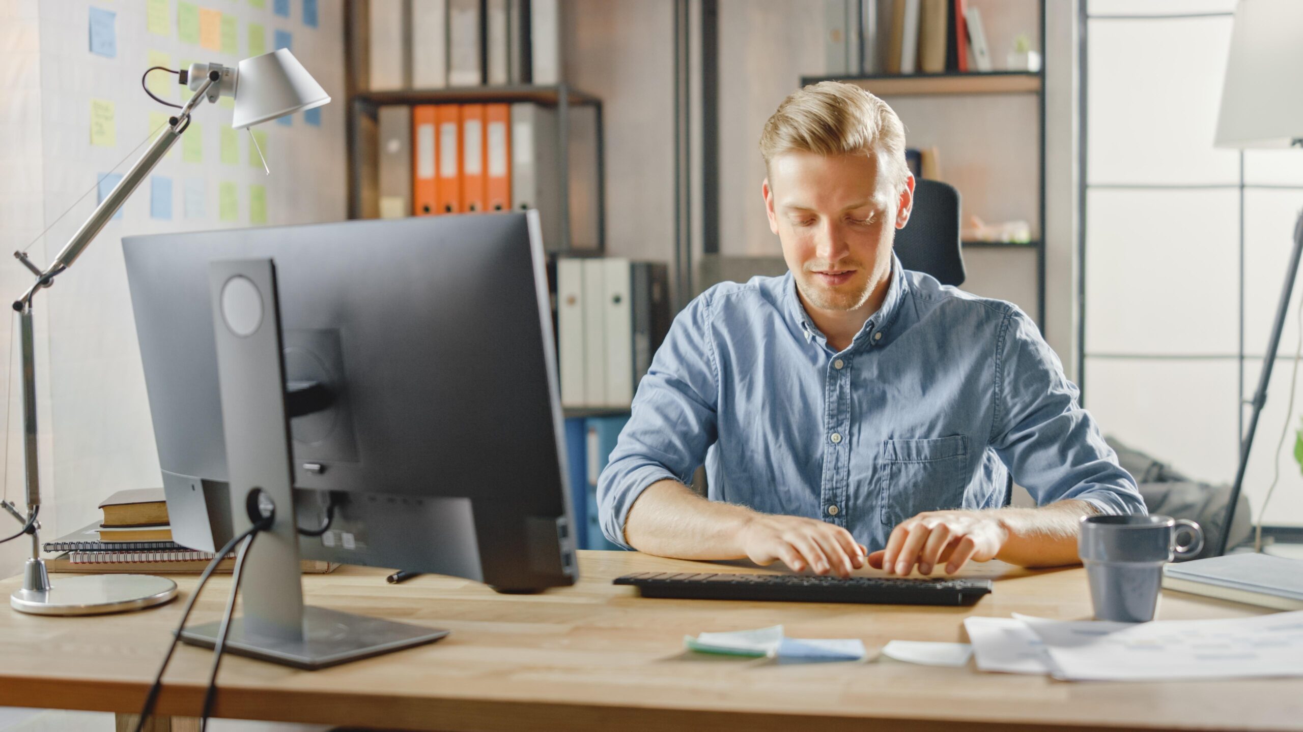 man-sits-desk-office-with-computer-monitor-box-paper-table